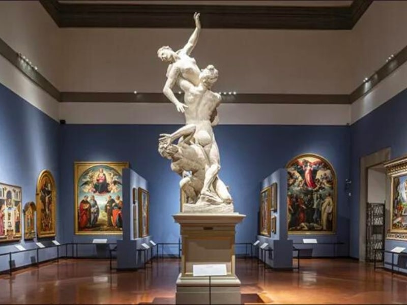 Statue of three people in a blue painted hall in a museum