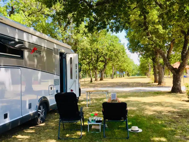 motorhome camping in a grassy field surrounded by large trees in France