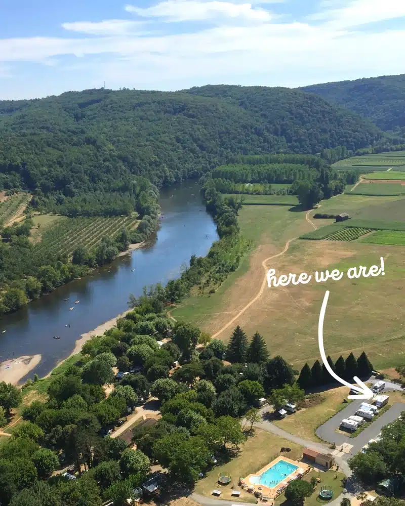 small motorhome parking place near a wide river surrounded by grassy fields