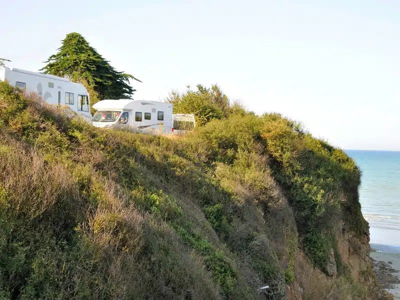 motorhomes parked by bushes at the edge of a small cliff and beach in notrh-eastern France