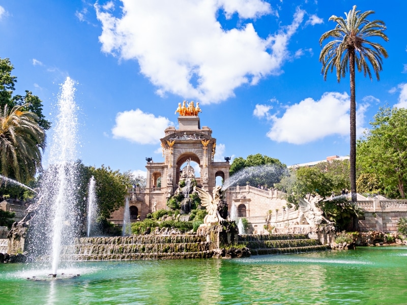 ornate fountain and arch with palm trees and a pond