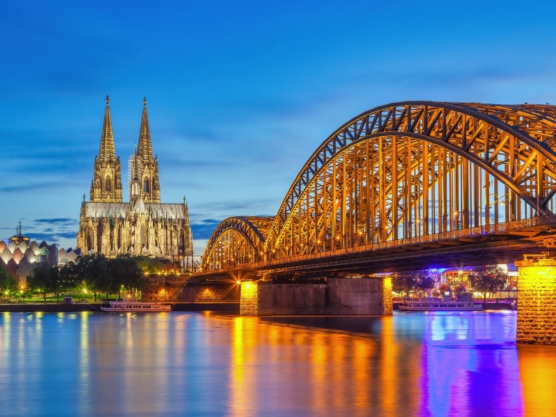 cathedral with double spire with a river and iron railway bridge in the foreground