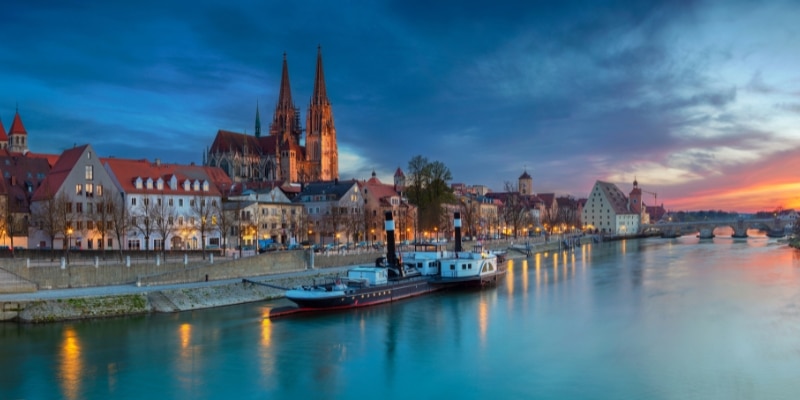 steam boat on a river at sunset with a church in the background