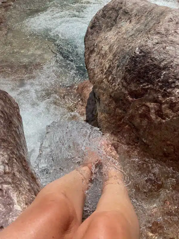 bare legs in rusging water between two limestone rocks