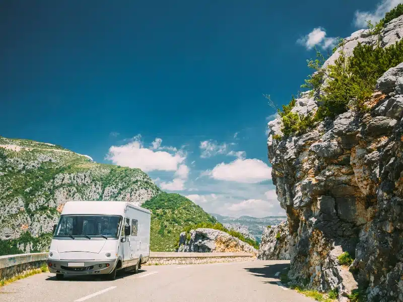 motorhome on a road surrounded by rocky crags and mountains