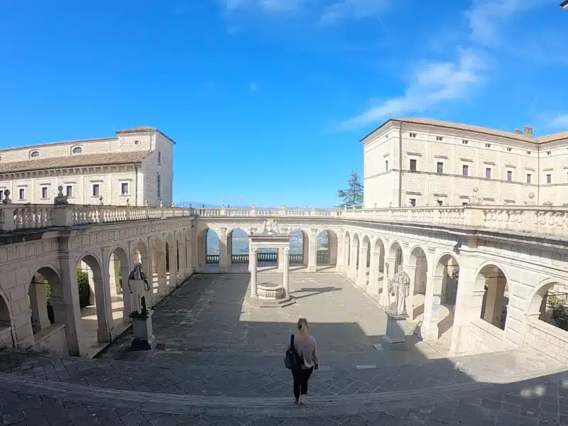 woman walking down steps through an arched courtyard with blue sky