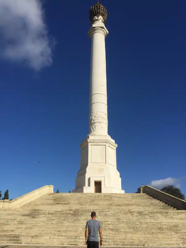 tall stone column with a globe on top and many steps leading to it