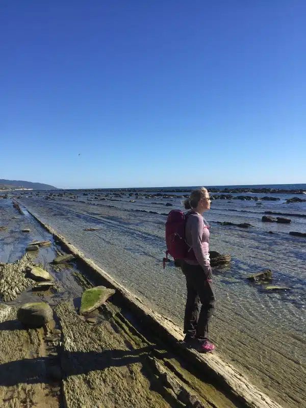 Woman standing on long straight rock formations in the sea