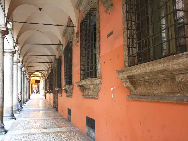 a portico of Bologna painted a striking terracotta colour, with barred windows and marble floor
