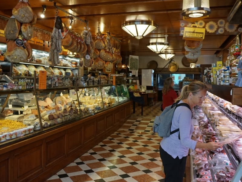 shopping in a delicatessen with a tiled floor and long glass counters full of ham, cheese and pasta