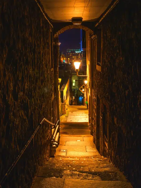 arched and covered stone alleyway at night