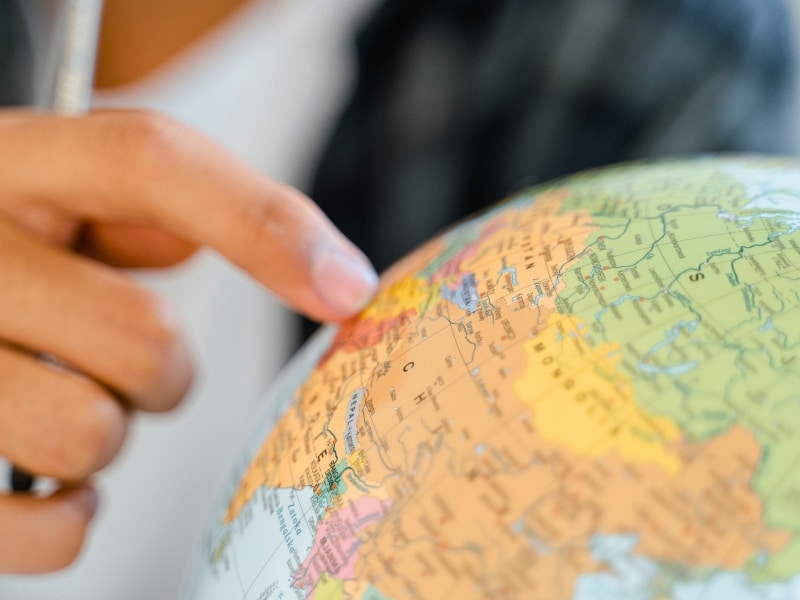 hand pointing at a place on a globe