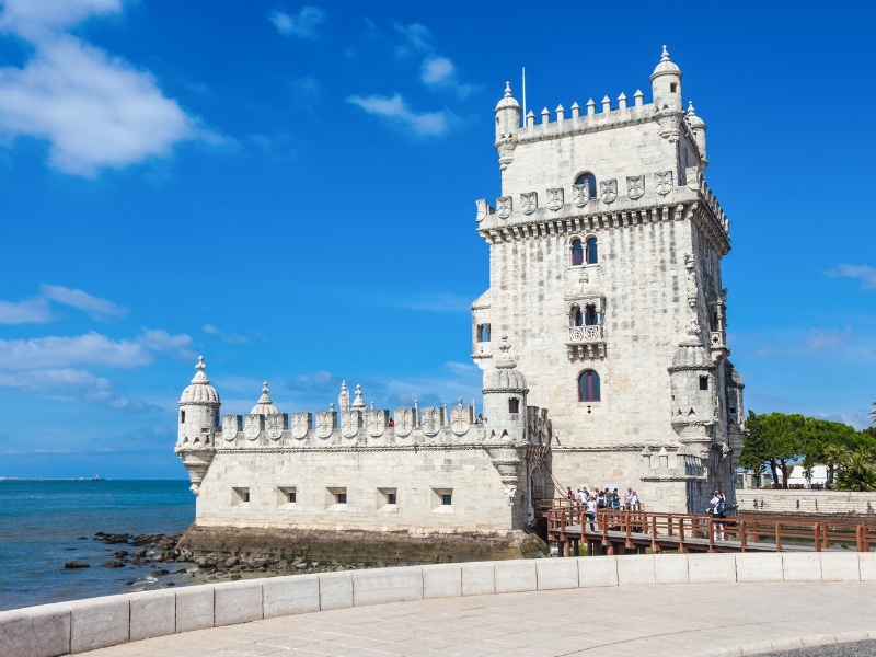 large square stone tower next to the sea
