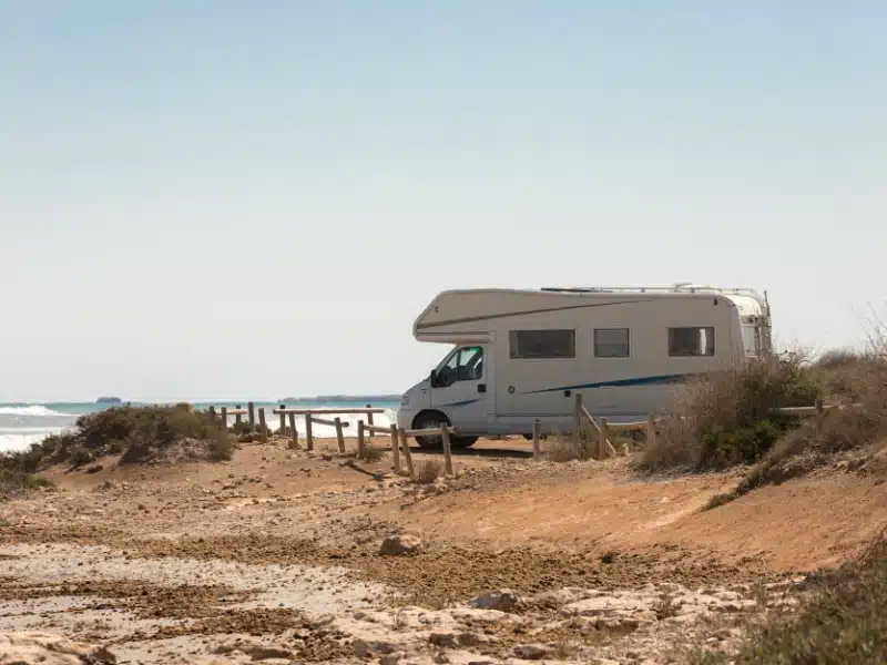 white motorhome parked on a beach with the sea in view