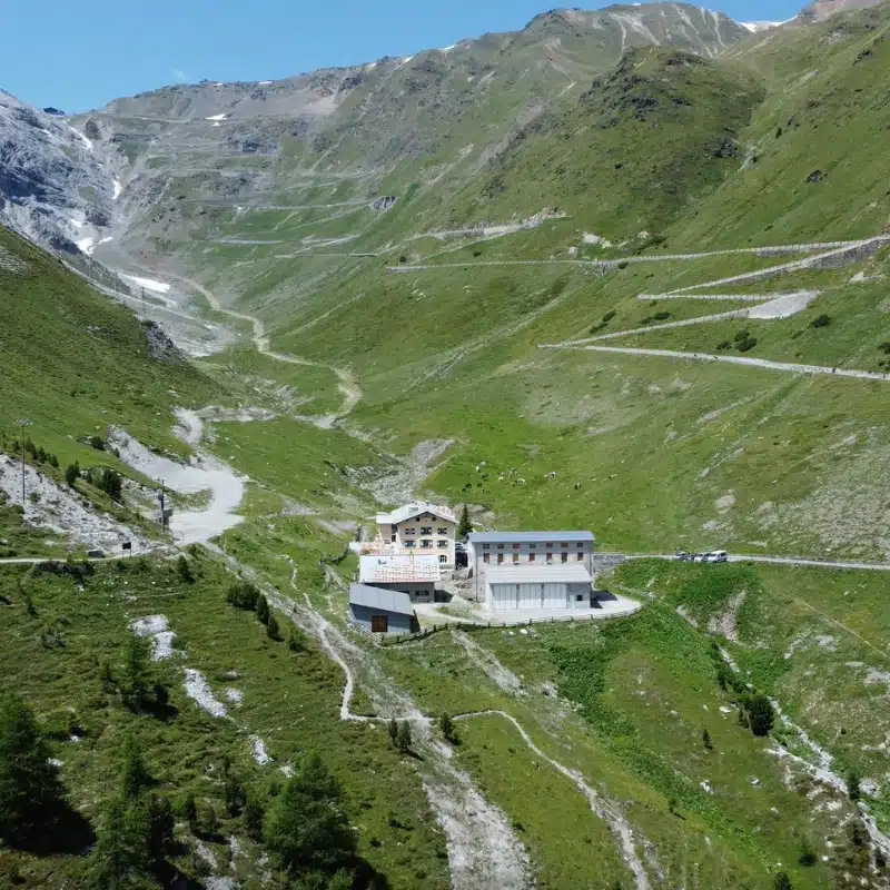 white hotel building at the bottom of a mountain pass