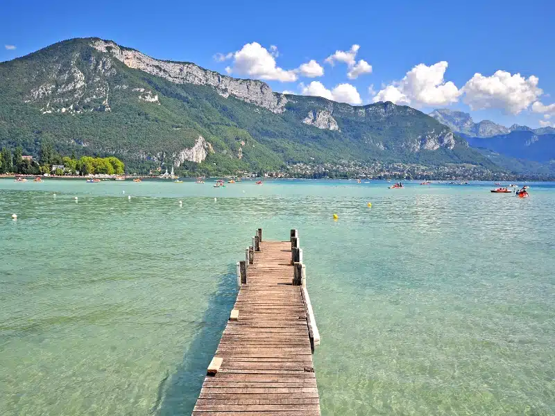 wooden pier into a clear lake with mountains in the background