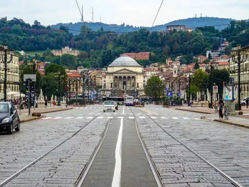 road towards a cream domed building with lines, pedestrian crossings and tram lines.