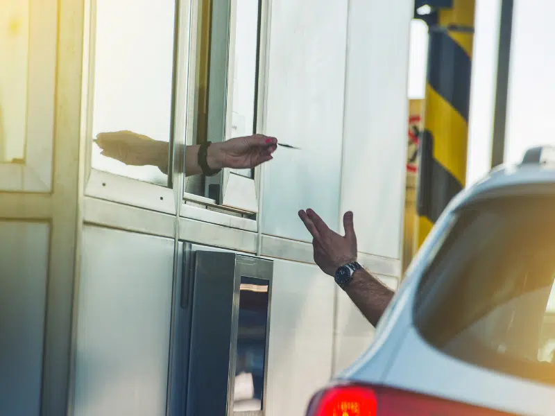 toll booth operator handing a ticket to a car driver