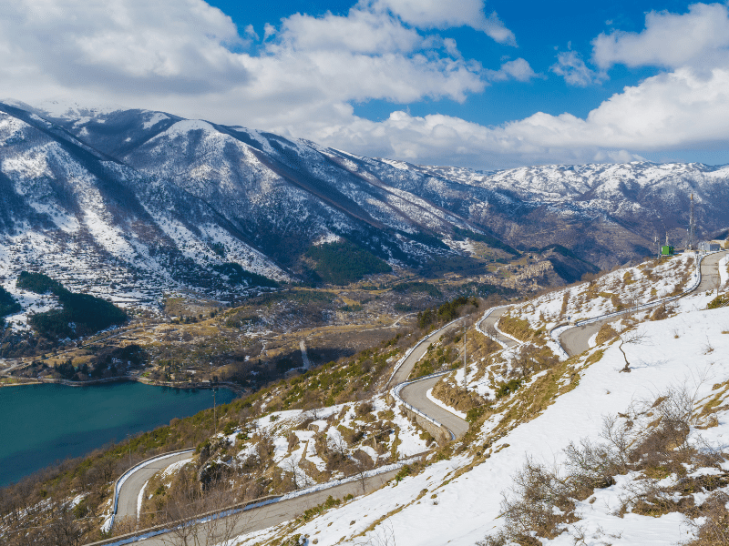 road through a mountainous scene with snow on the ground
