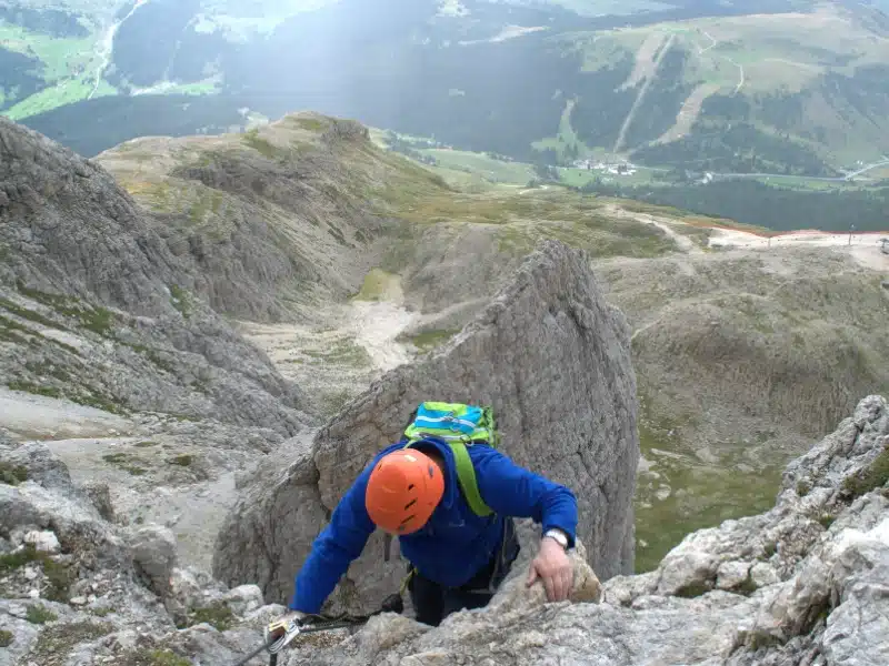 person wearing an orange helmet climing in the alps