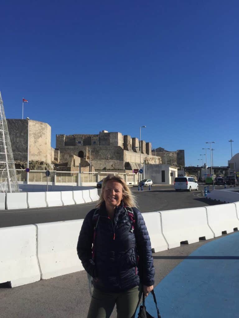 Woman in a blue coat in a town with an historic castle in the background