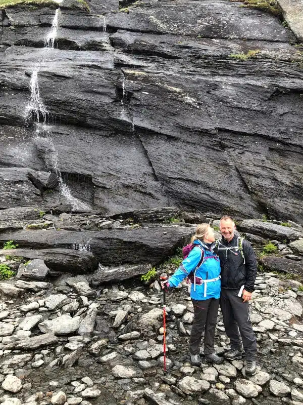 couple hiking amidst dark rocks and waterfalls