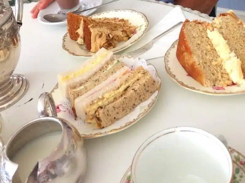 finger sandwiches and cake on plates on a white tabel cloth