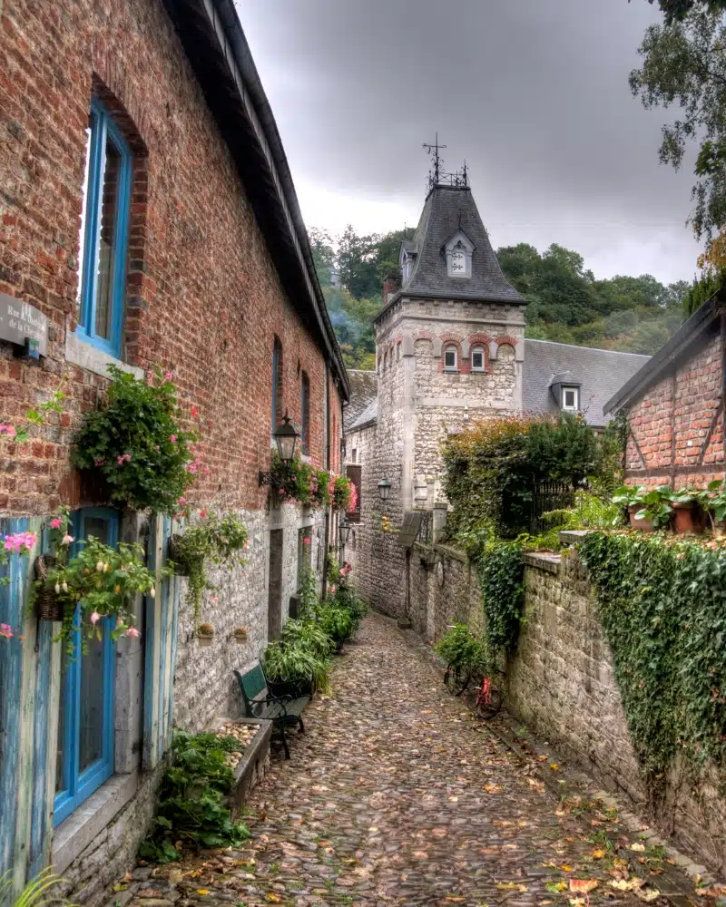 village houses along a cobbled street and a stone wall with a tower behind