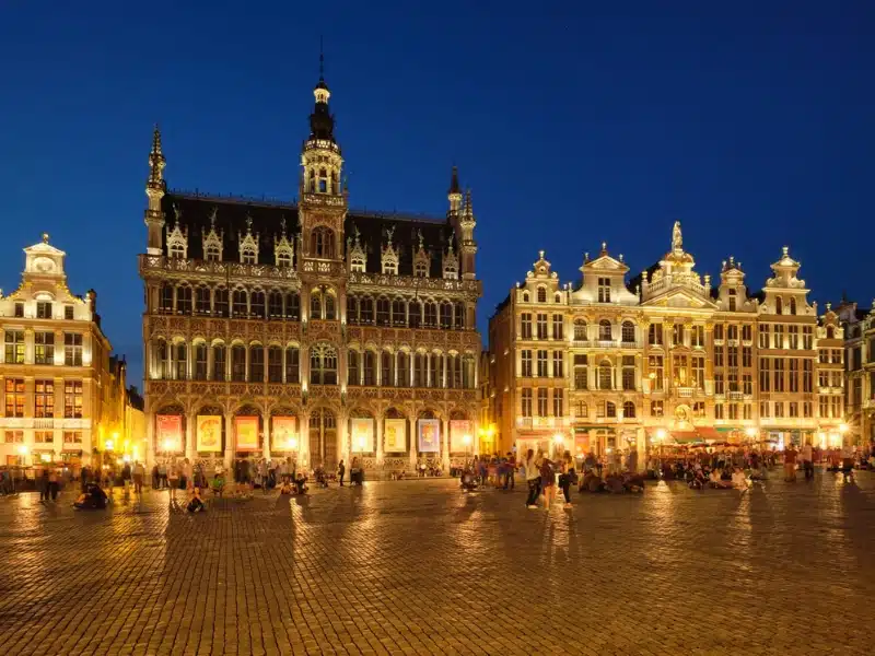 historic buildings surrounding a large city square full of people at night