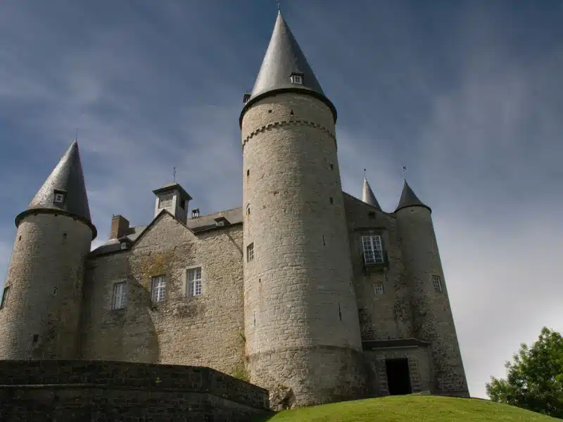 large stone house with four round towers topped with conical metal roofs