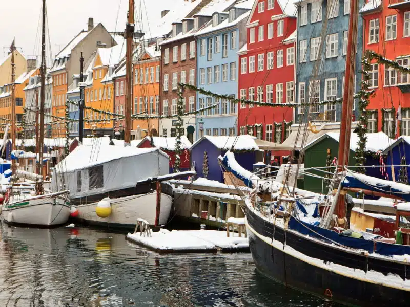 boats in a canal lined with colorful houses, decorated for Christmas