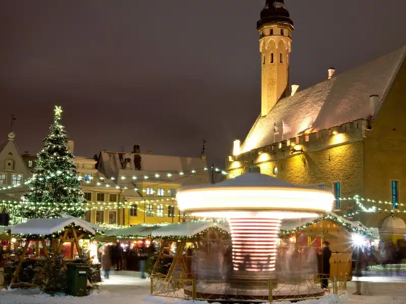 Christmas lights and decorations in a snowy square with a church in the background