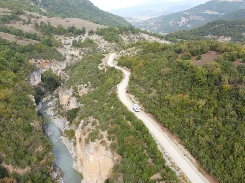 overland truck on a road following a deep river canyon