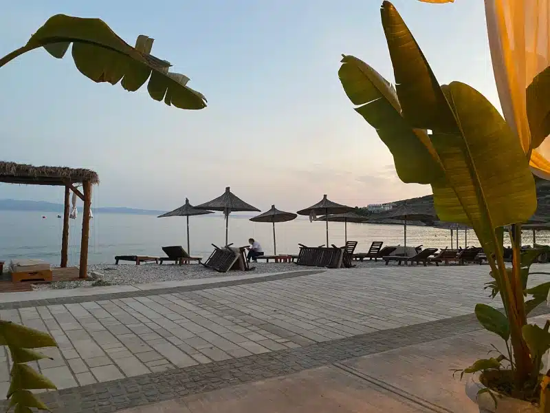 a beach with chars and parasols at dusk