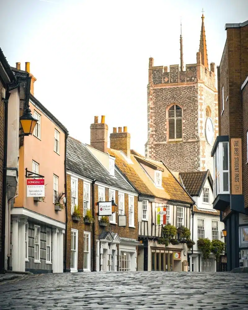 cobbled street steching down a hill with historic buildings and a church in the distance