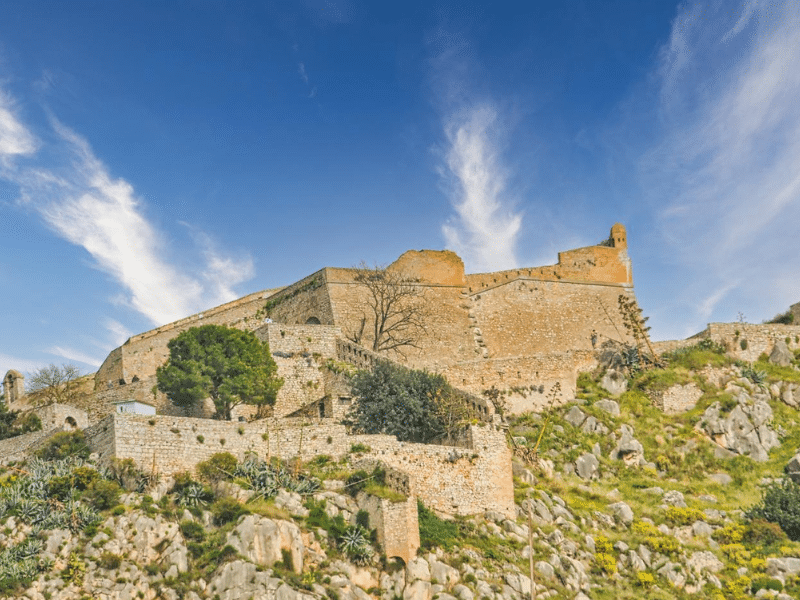large stone castle on a rocky green hillside