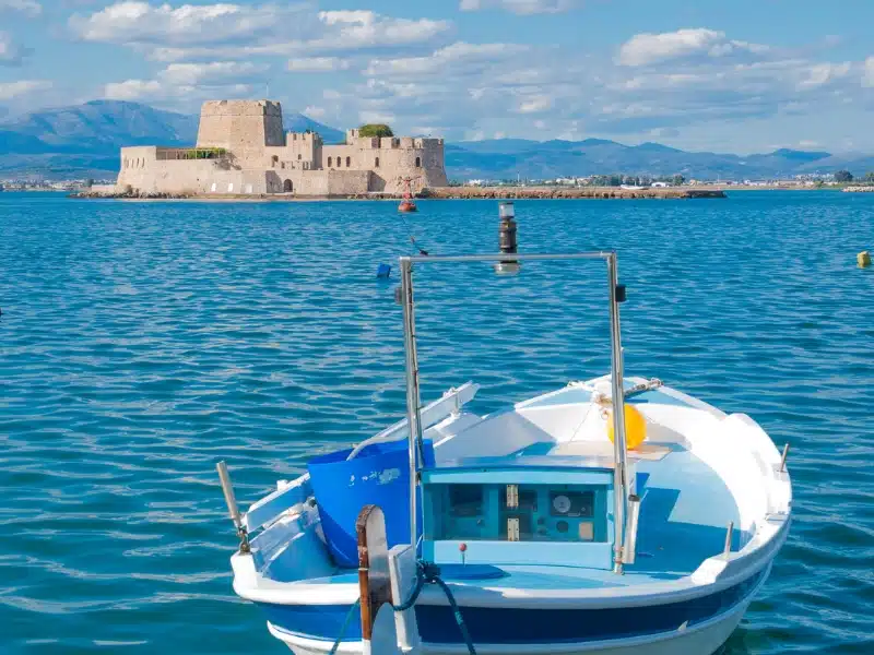 blue and white speed boat with a small castle islet in the distance