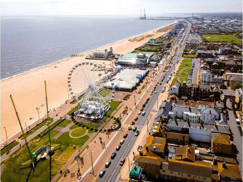 Large sandy beach backed by fairground rides, amusement parks and gardens