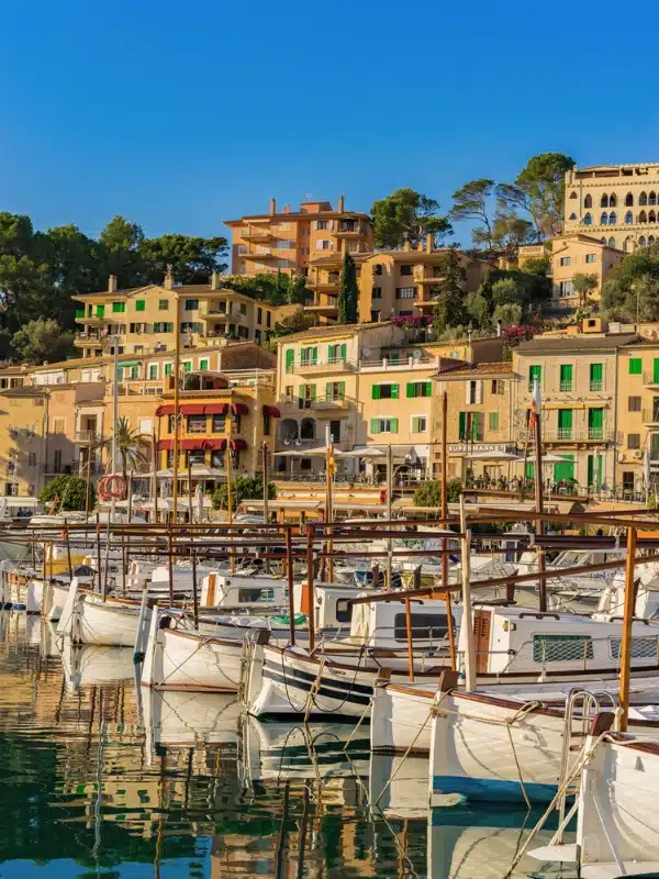 stacked houses with colorful painted shutters with a marina full of traditional wooden boats in the foreground