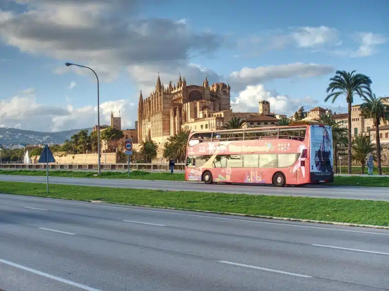 red double-decker bus on a road outside a large stone church