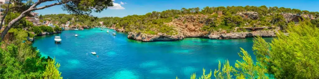 turquoise bay with boats surrounded by a rocky shore line