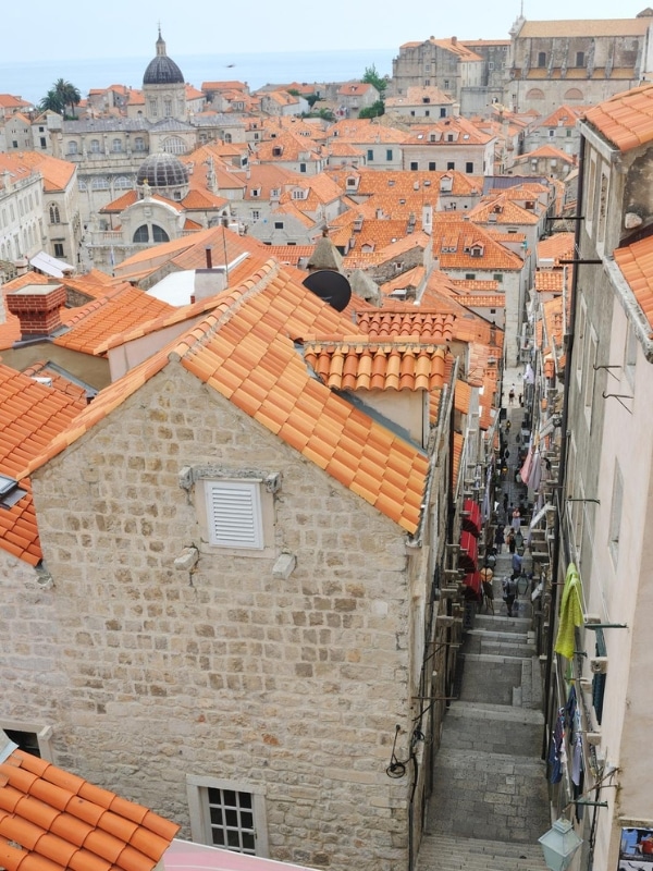 red roofs over creamy stone buildings and a church in the distance