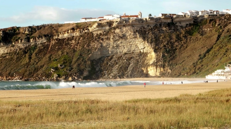 beach backed by grass and cliffs