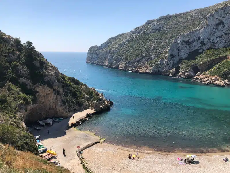 turquoise bay with rocky cliffs at each side and a pebbly beach