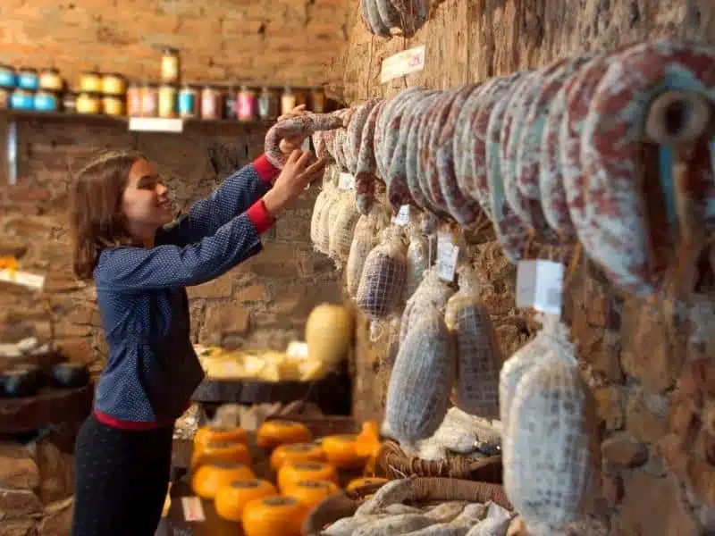 woman in a rustic shop with cheese and sausages
