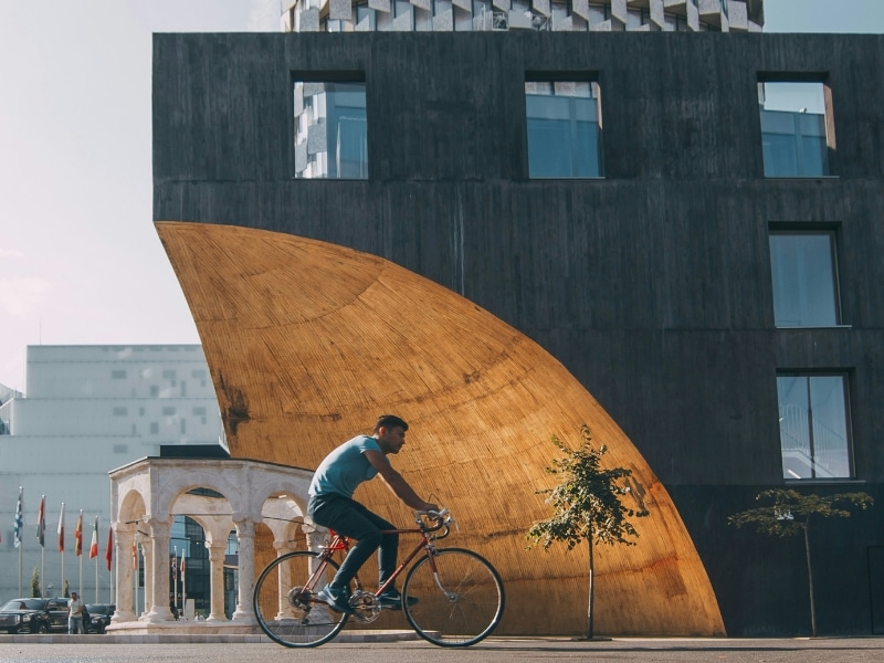 man on a bicycle cycling past a modern building