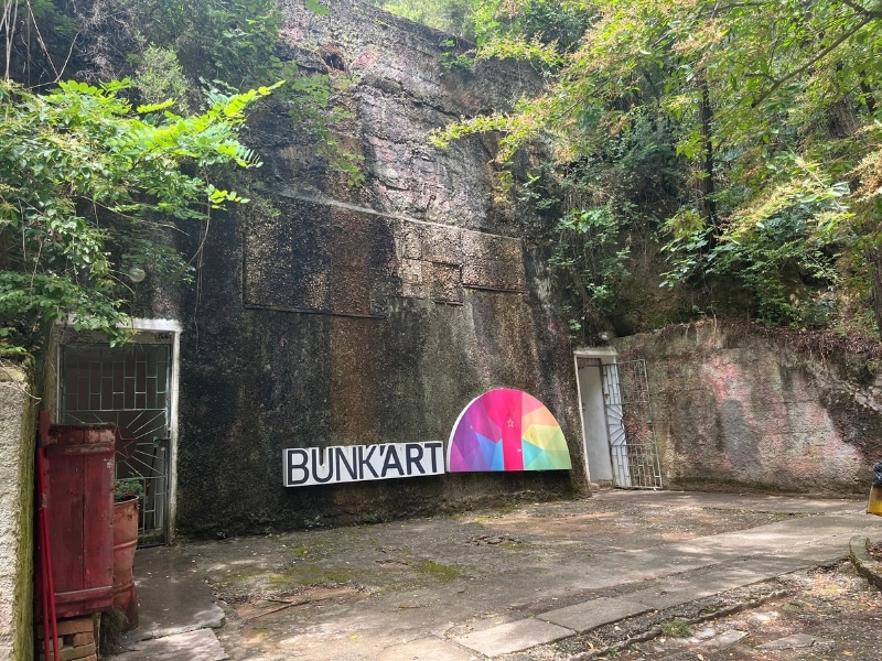 deep concrete bunker with two doors and a colorful sign