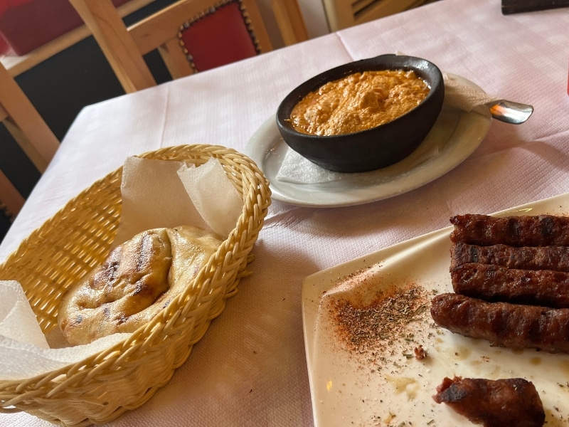 food on a table with sausages and a basket of bread