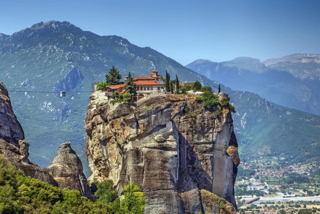 red roofed building surrouned by green trees and vegetation on top of a tall rock