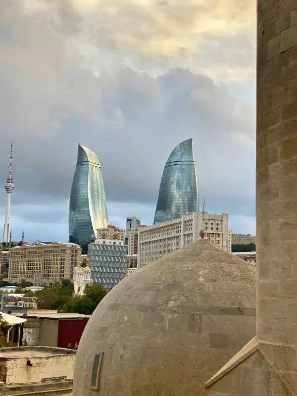 tall glass flame towers seen over ancient stone buildings